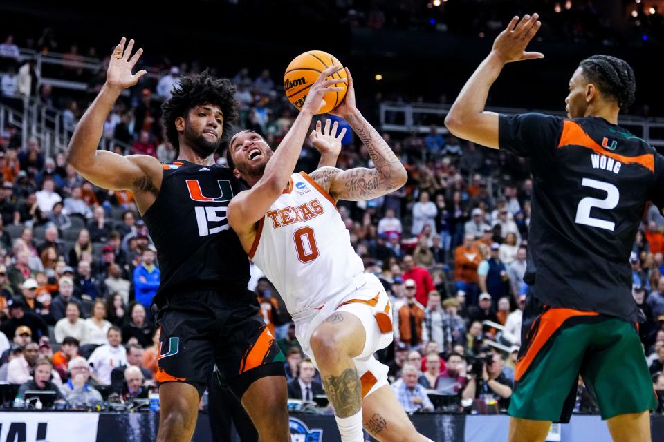 Texas forward Timmy Allen (0) drives to the basket past Miami forward Norchad Omier (15) as Miami guard Isaiah Wong (2) reacts during their Elite Eight game.