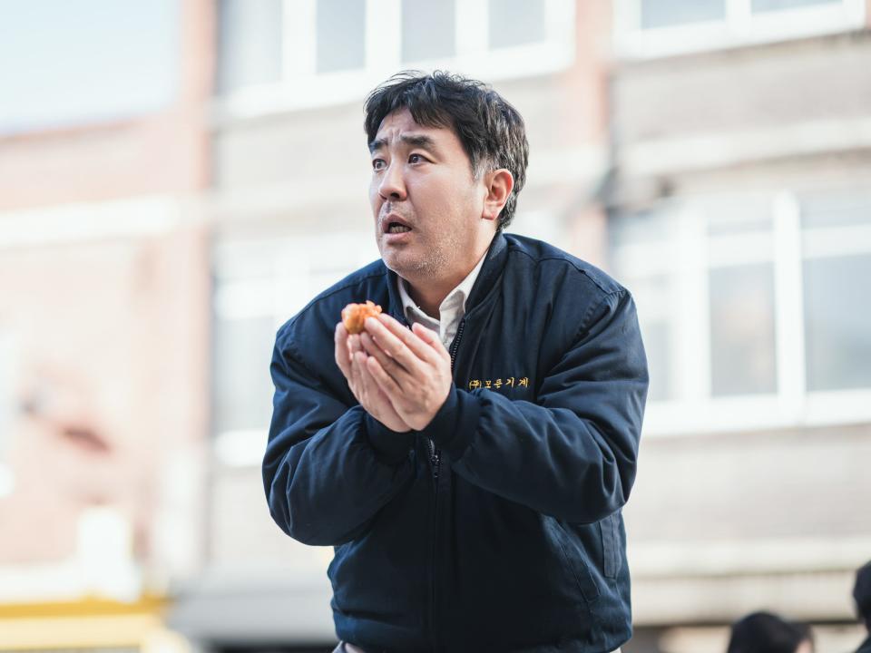 ryu seung-ryong as choi sun-man, a middle aged man with some beard scruff looking panicked and cradling a chicken nugget in his hands
