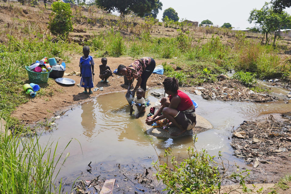 Women wash clothes and dishes in a stream in Bouar, Central African Republic, Thursday, March 7, 2024. Nearly 5,000 fighters have put down their arms in Central African Republic since a disarmament program launched nearly a decade ago. Yet former rebels, communities and conflict experts say it's hard to halt fighting in a country still in conflict and where little other paid work exists. (AP Photo/Sam Mednick)