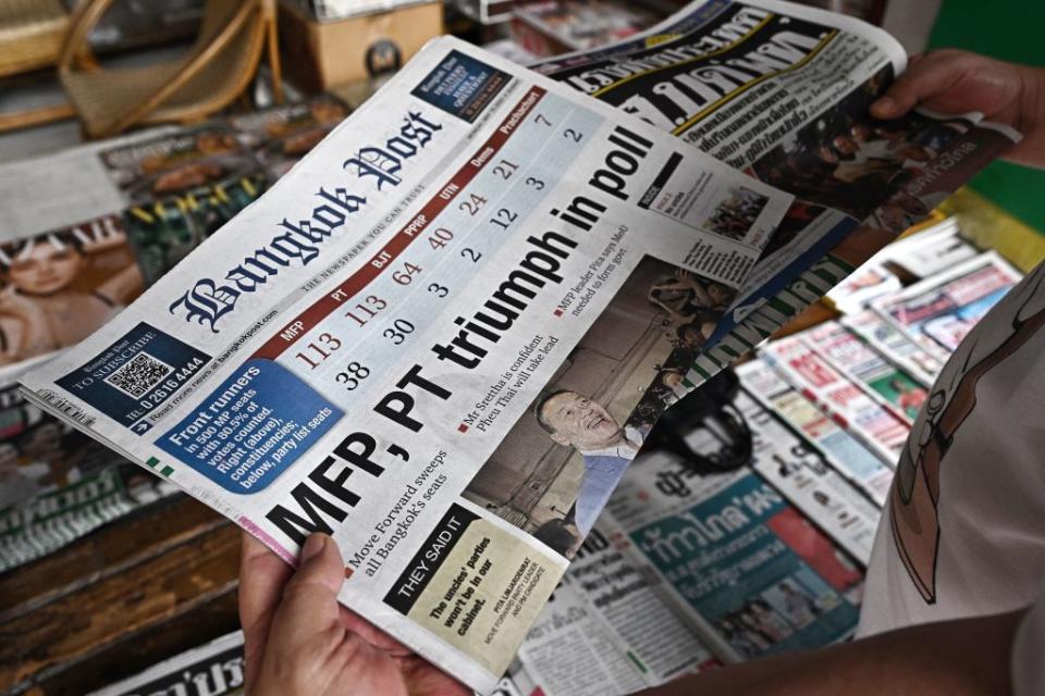 A man reads a Thai newspaper featuring front page coverage of Thailand's general election results, at a newsstand in Bangkok on May 15, 2023.<span class="copyright">Lillian Suwanrumpha—AFP/Getty Images</span>