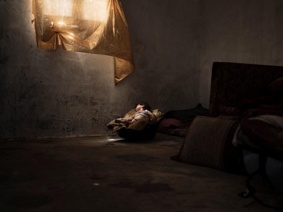 A toddler sleeps in an old car seat in a darkened room (Paddy Dowling)