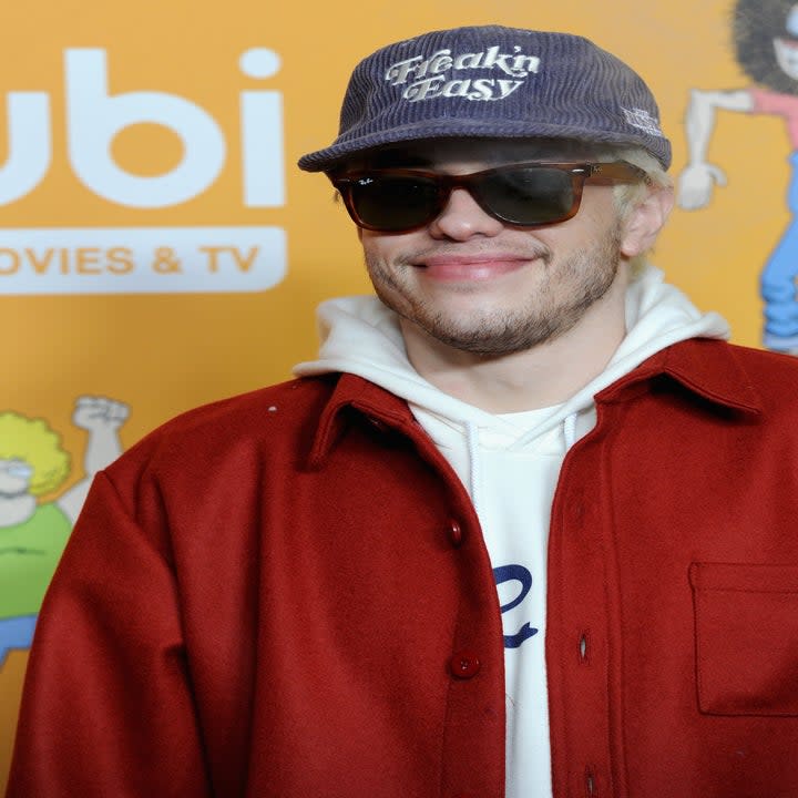 Pete Davidson smiling in a hoodie at a red carpet event
