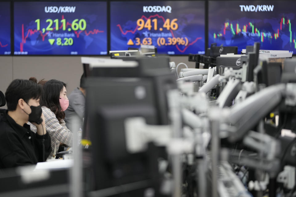 Currency traders watch computer monitors near screen showing the foreign exchange rate between U.S. dollar and South Korean won, left, at a foreign exchange dealing room in Seoul, South Korea, Wednesday, March 30, 2022. Asian stock markets followed Wall Street higher on Wednesday as talks on ending Russia's war on Ukraine appeared to make progress. (AP Photo/Lee Jin-man)