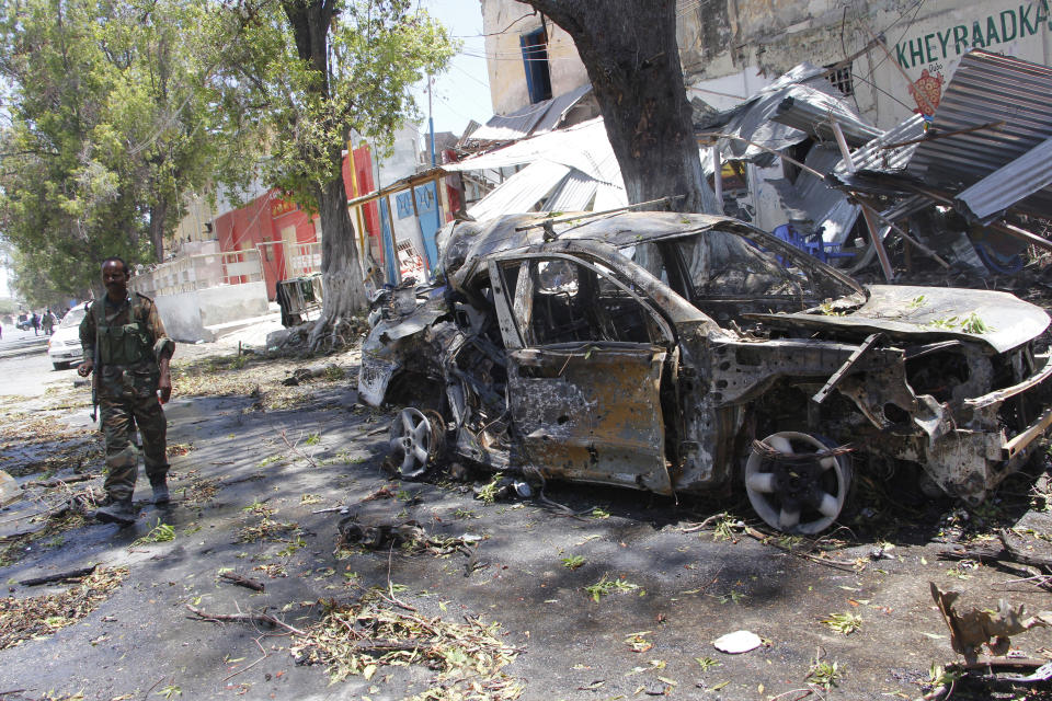 A Somali soldier walks near the wreckage of car in Mogadishu, Somalia, Thursday March 7, 2019. A Somali police officer says a car bomb blast near a security checkpoint near the presidential palace in the Somali capital killed at least two people. (AP Photo/Farah Abdi Warsameh)