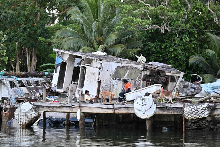 Residentes sentados en un muelle frente a botes abandonados en las afueras de Suva, la capital de Fiji