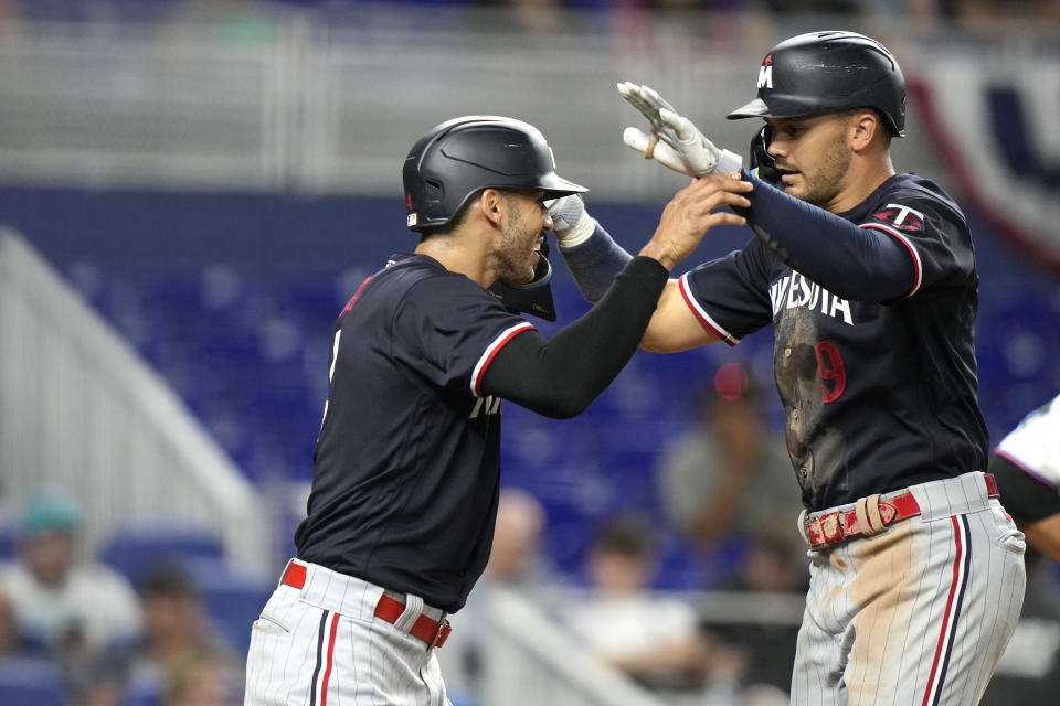 Minnesota Twins' Carlos Correa, left, greets Trevor Larnach at the plate after Larnach hit a two-run home run during the seventh inning of a baseball game against the Miami Marlins, Monday, April 3, 2023, in Miami. (AP Photo/Lynne Sladky)