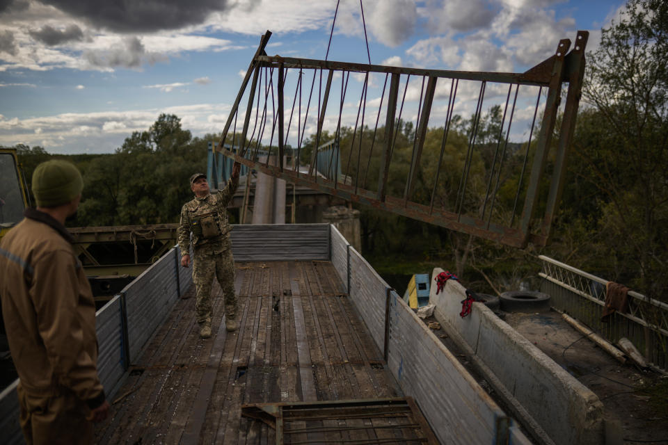 Ukrainian soldiers remove metal structure pieces as they work on a bridge damaged during fighting with Russian troops in Izium, Ukraine, Monday, Oct. 3, 2022. (AP Photo/Francisco Seco)