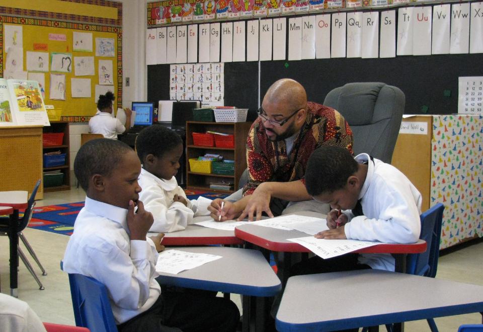 FILE - In this March 15, 2011 file photo, teacher Calvin Hobbs works with students at African-centered Timbuktu Academy of Science and Technology in Detroit. A proposal that Gov. Rick Snyder commissioned for overhauling public education in Michigan and change how the state pays for student learning was released Monday, Nov. 19, 2012. The Oxford Foundation-Michigan placed a draft of the Michigan Public Education Finance Act on its website. If legislators approve it, the proposal would replace the School Aid Act of 1979. (AP Photo/Corey Williams, File)