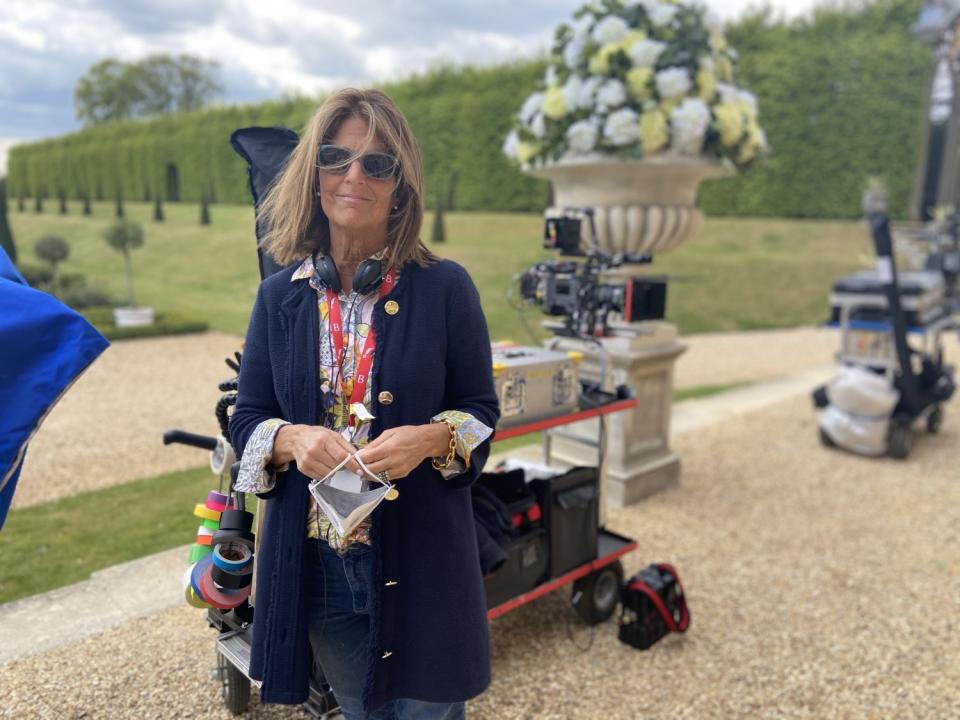 A woman with headphones around her neck stands on a film set.