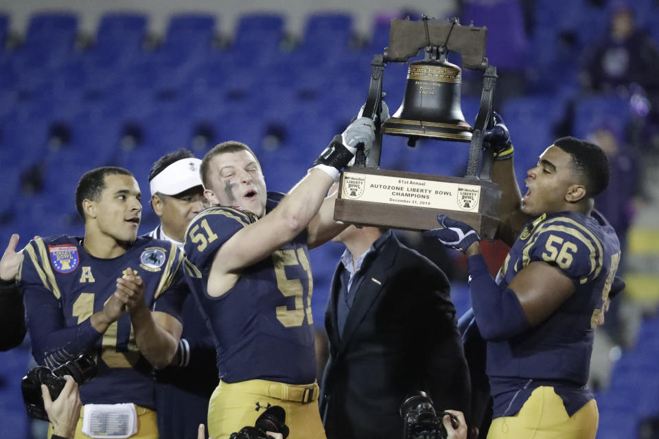 Navy linebacker Paul Carothers (51) and linebacker Nizaire Cromartie (56) lift the trophy after Navy beat Kansas State in the Liberty Bowl NCAA college football game Tuesday, Dec. 31, 2019, in Memphis, Tenn. At left is quarterback Malcolm Perry (10). Navy won 20-17. (AP Photo/Mark Humphrey)