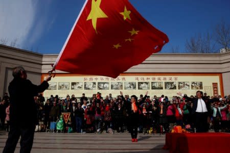 FILE PHOTO:  A man waves the Chinese national flag as an amateur choir performs in a park in a residential neighbourhood in Beijing, China February 28, 2017.  REUTERS/Thomas Peter