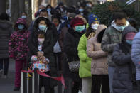 Residents line up in freezing cold temperatures for their routine COVID-19 throat swabs at a coronavirus testing site in Beijing, Sunday, Dec. 4, 2022. China on Sunday reported two additional deaths from COVID-19 as some cities move cautiously to ease anti-pandemic restrictions amid increasingly vocal public frustration over the measures. (AP Photo/Andy Wong)