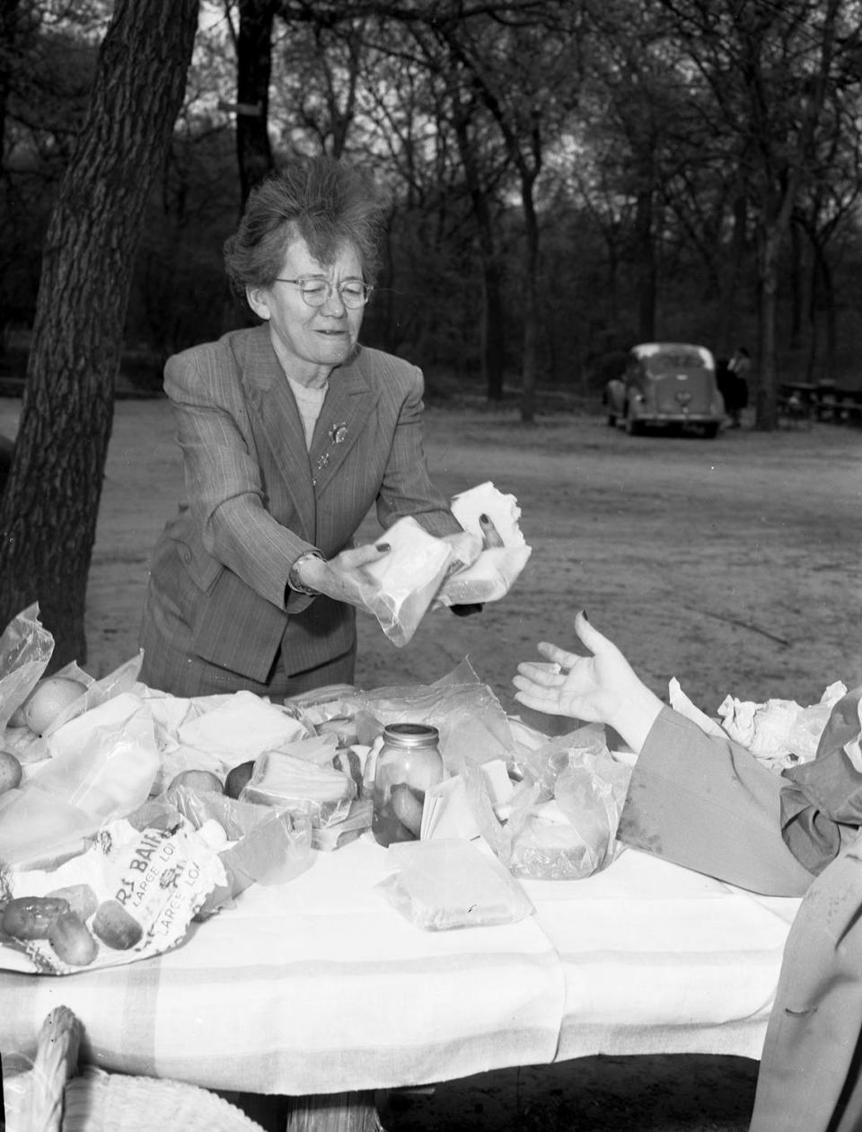 April 3, 1947: It was “Decatur Day” at Forest Park Zoo on Thursday. Decatur school teacher, Miss Bell Ford, brought a group of fifth-graders on a field trip to enjoy the day. Miss Ford is shown setting up a picnic lunch underneath the trees. On the table are sandwiches, fruit, and pickles.