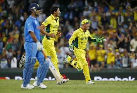 Australia's Mitchell Starc (C) and Brad Haddin celebrate after India's captain MS Dhoni (L) was run out by Glenn Maxwell during their Cricket World Cup semi-final match in Sydney March 26, 2015. REUTERS/David Gray