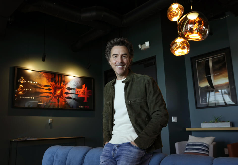 Producer-director Shawn Levy poses for a portrait in his office, Thursday, Oct. 12, 2023, in West Hollywood, Calif., to promote his limited-series "All the Light We Cannot See" based on the best-selling novel. Behind him are artworks for two projects on which he served as a producer, the 2016 film "Arrival," right, and the Netflix series "Stranger Things." (AP Photo/Chris Pizzello)