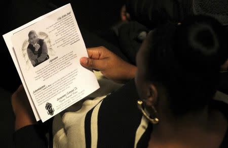 A mourner reads the obituary from the program during the funeral service for Tamir Rice in Cleveland, Ohio December 3, 2014. REUTERS/Aaron Josefczyk