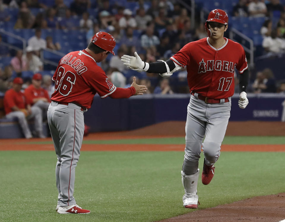 Los Angeles Angels' Shohei Ohtani (17), of Japan, shakes hands with third base coach Mike Gallego (86) after Ohtani hit a three-run home run off Tampa Bay Rays' Ryan Yarbrough during the first inning of a baseball game Thursday, June 13, 2019, in St. Petersburg, Fla. (AP Photo/Chris O'Meara)