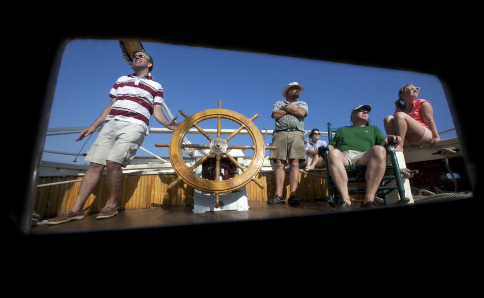 In this photo made Friday, Aug. 3, 2012, passenger Paul Ernest of Lynnfield, Mass., left, takes a turn at the helm during a three-day cruise on the schooner Mary Day on Penobscot Bay off Camden, Maine. The 90-foot Mary Day, which is celebrating its 50th season, is the first schooner in the Maine windjammer fleet to be built specifically to accommodate passengers. Its sleeping cabins are heated and have nine feet of headroom. (AP Photo/Robert F. Bukaty)