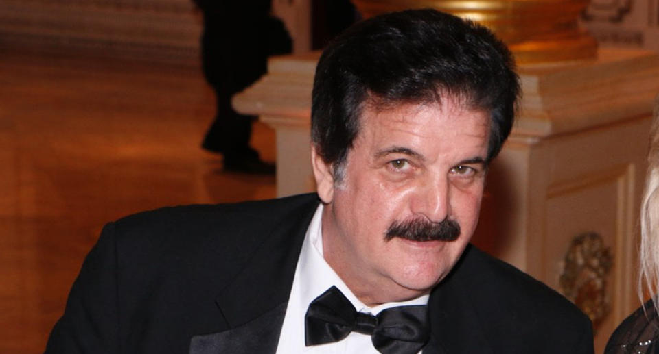 Photo of Dick Farrel, with dark hair and a moustache, wearing a suit and looking at the camera.