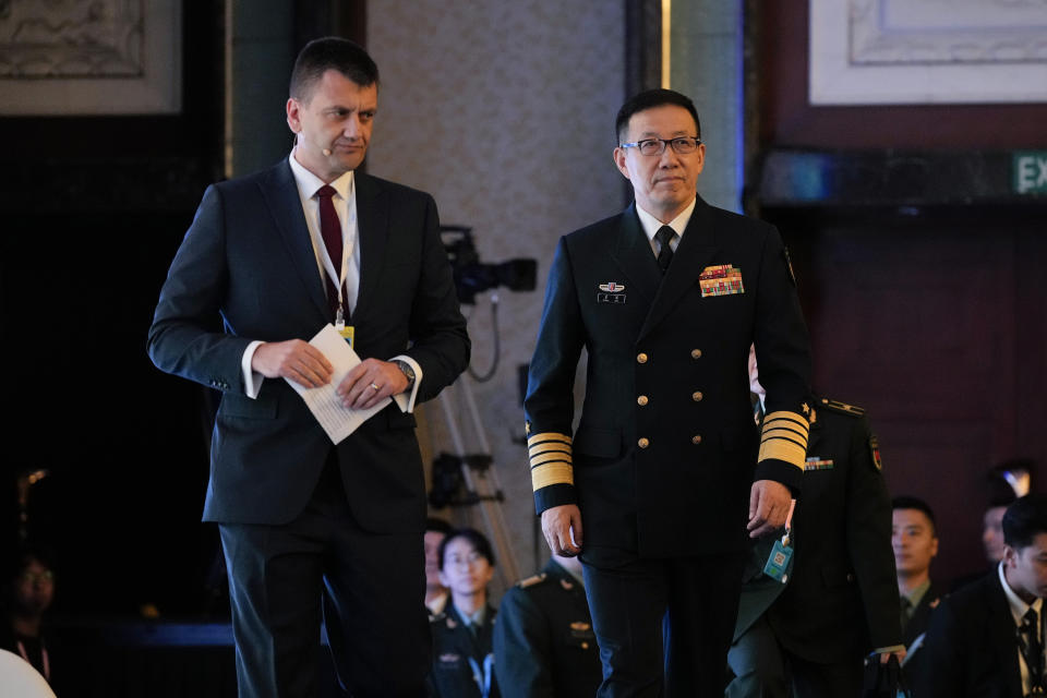 China's Defense Minister Dong Jun, right, walks on stage during the Shangri-La Dialogue summit at the Shangri-La Hotel in Singapore, Sunday, June 2, 2024. (AP Photo/Vincent Thian)