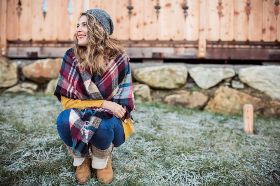 Woman on vacation at mountain cabin. Standing in front of house and enjoying in winter morning. Grass is coverd with frost. Austrian Alps.