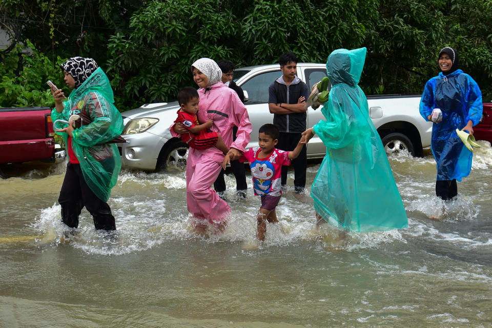 Bewohner laufen durch eine überschwemmte Stadt im Süden Thailands. - Copyright: MADAREE TOHLALA / Kontributor / Getty Images