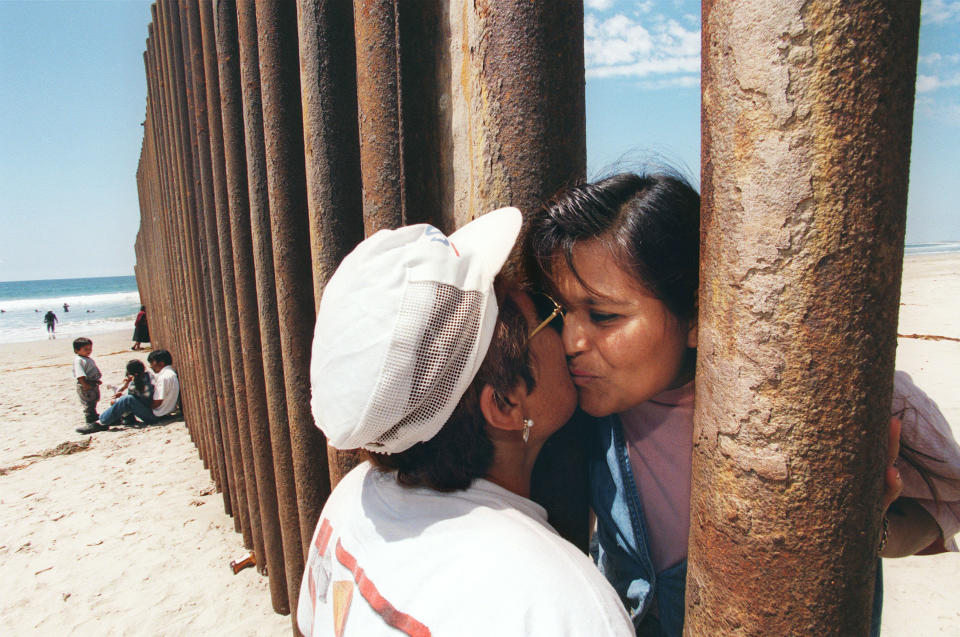 Esther Pereyra Rubalcaba (left) kisses her daughter Patricia through the wall separating the US and Min Tijuana, Mexico.