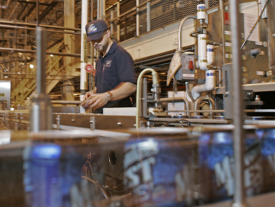 FILE This June 13, 2005 file photo shows Miller brewery worker Steve Greene looking over cans as they go by on the line at Miller Brewing Company in Milwaukee. The brewery offers an indoor and outdoor guided walking tour featuring sights of the high-speed packaging lines, the shipping distribution center with typically a half million cases of beer, a cave where beer was stored before mechanical refrigeration and the brew house. (AP Photo/Morry Gash, file)