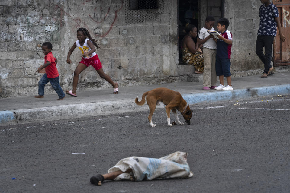 En esta imagen de archivo, las piernas de un hombre descuartizado asoman de una bolsa arrojada en una calle con niños jugando y perros, en el vecindario de Colinas de la Florida, en Guayaquil, Ecuador, el 1 de octubre de 2023. (AP Foto/Rodrigo Abd, archivo)