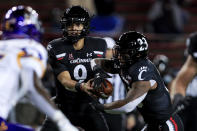 Cincinnati quarterback Desmond Ridder hands off the ball to running back Gerrid Doaks, right, during the first half of the team's NCAA college football game against East Carolina, Friday, Nov. 13, 2020, in Cincinnati. (AP Photo/Aaron Doster)