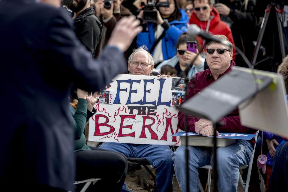 A man with breathing tubes holds up a sign that reads "Feel the Bern" as Democratic presidential candidate Sen. Bernie Sanders, I-Vt., left, speaks at a campaign stop at the Bernie 2020 Cedar Rapids Field Office, Sunday, Feb. 2, 2020, in Cedar Rapids, Iowa. (AP Photo/Andrew Harnik)