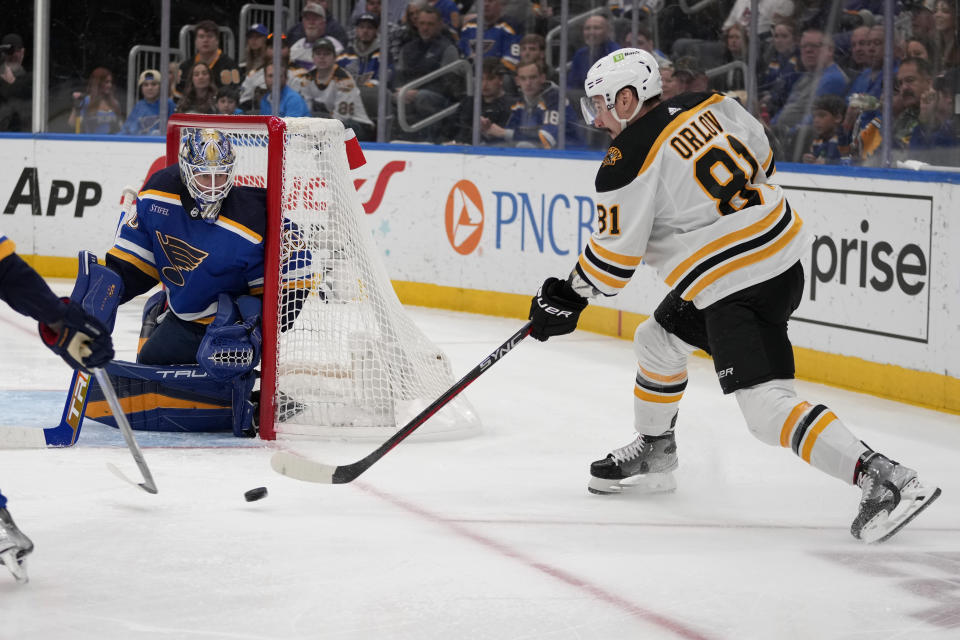 Boston Bruins' Dmitry Orlov (81) passes as St. Louis Blues goaltender Jordan Binnington defends during the first period of an NHL hockey game Sunday, April 2, 2023, in St. Louis. (AP Photo/Jeff Roberson)