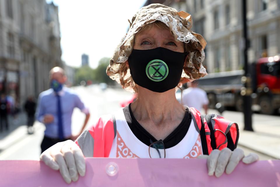 An activist from the climate protest group Extinction Rebellion poses with a banner in central London on September 1, 2020, as they start their new season of "mass rebellions". - Climate protest group Extinction Rebellion will target Britain's parliament as part of "mass rebellions" starting from September 1. Other actions will take place around the country. (Photo by ISABEL INFANTES / AFP) (Photo by ISABEL INFANTES/AFP via Getty Images)