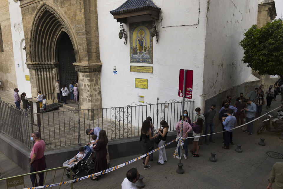 Catholic worshipers queue to enter the Omnium Sanctorum church during the Holy Week in Seville, southern Spain, Tuesday, March 30, 2021. Few Catholics in devout southern Spain would have imagined an April without the pomp and ceremony of Holy Week processions. With the coronavirus pandemic unremitting, they will miss them for a second year. (AP Photo/Laura Leon)
