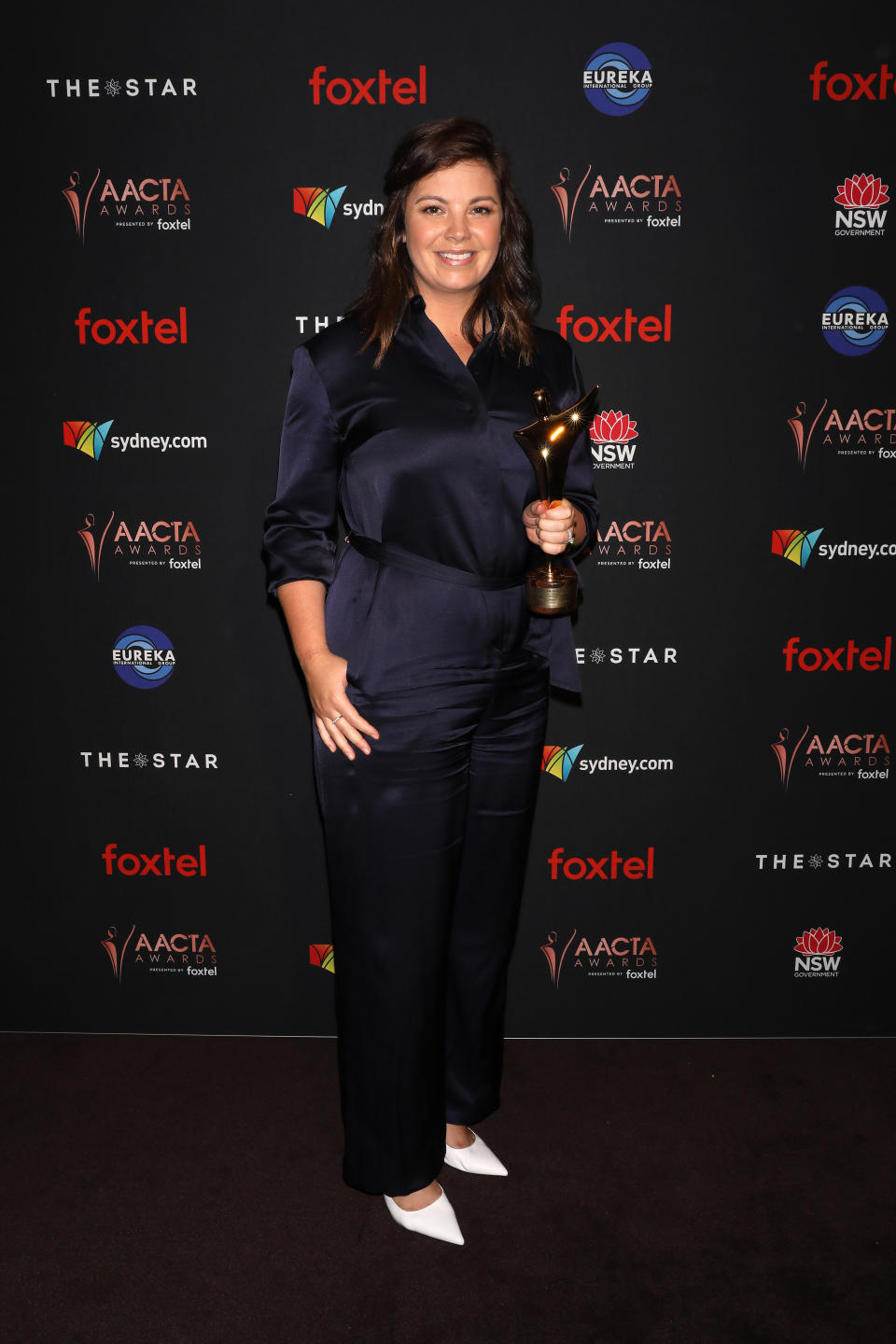 Yvonne Sampson poses and smiles with the AACTA Award for Best Female Presenter in the media room.