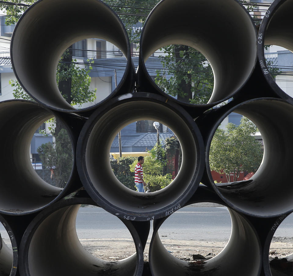 <p>A Nepalese man walks on the street seen through drinking water pipes piled at the road side in Kathmandu, Nepal, May 24, 2017. Nepal’s government is replacing all underground water pipe lines in Kathmandu which is expecting to end the acute water crisis in Kathmandu. (Photo: Narendra Shrestha/EPA) </p>