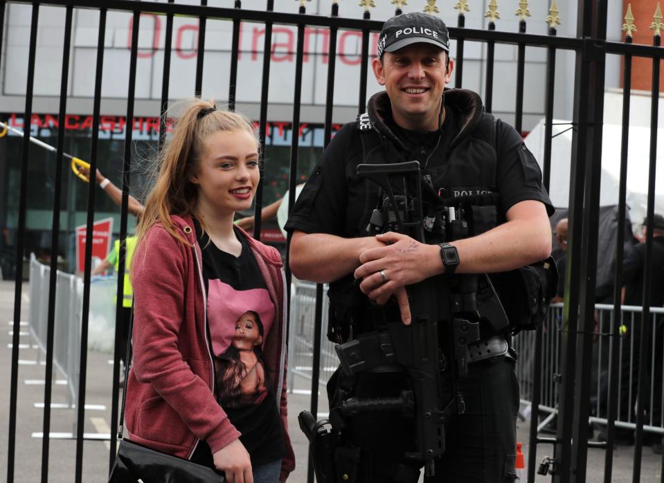 <p>Emma Prigg, 14, from Stoke-on-Trent, stands next to an armed police officer before the One Love Manchester benefit concert (PA) </p>