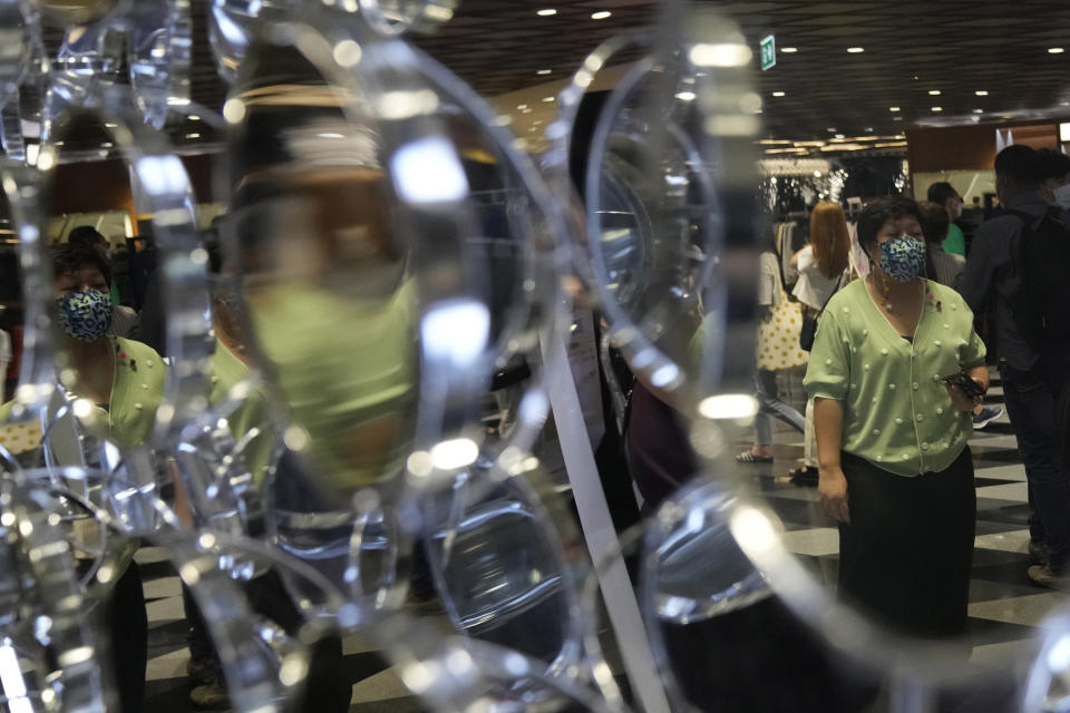 Customers wearing face masks are reflected in a mirror at Siam Center shopping mall in Bangkok, Thailand, Friday, Sept. 23, 2022. Thai officials announced Friday that Sept. 30 will mark the last day of a state of emergency originally imposed to control the spread of the coronavirus, as they also drop virtually all restrictions, such as entry requirements for visitors from abroad. (AP Photo/Sakchai Lalit)