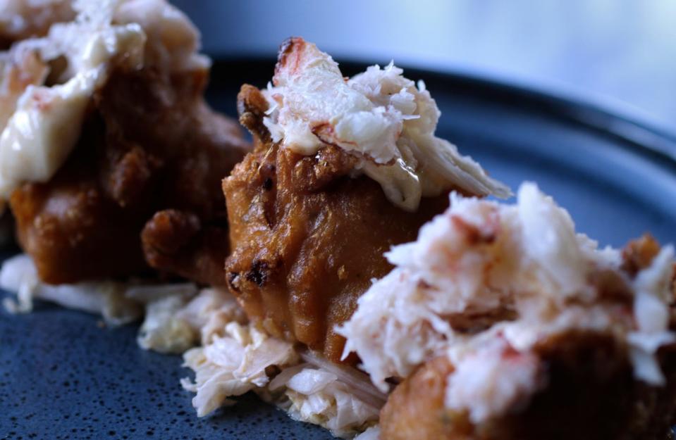 Crab Fritters topped with crab meat and Cajun aioli sit on a bed of Napa slaw.