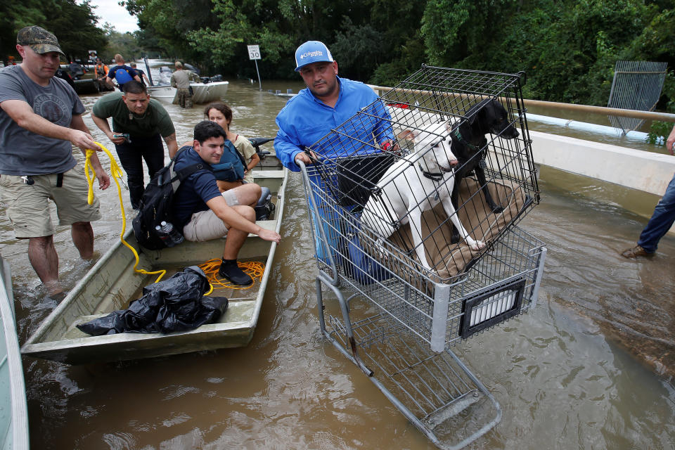 People unload belongings and dogs to cross a bridge to evacuate from the rising waters of Buffalo Bayou following Hurricane Harvey in a neighborhood west of Houston, Texas, U.S., August 30, 2017. REUTERS/Carlo Allegri