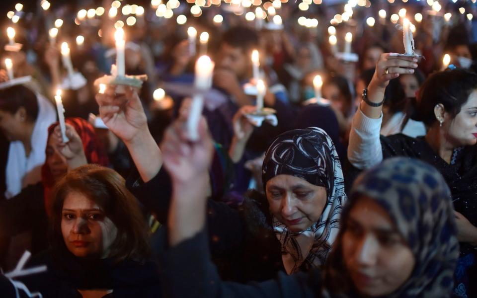 Paramedic staff members participate in a candelight vigil for the victims who lost their lives during an attack by a group of lawyers on Punjab Institute of Cardiology (PIC), in Lahore on December 13, 2019 - AFP