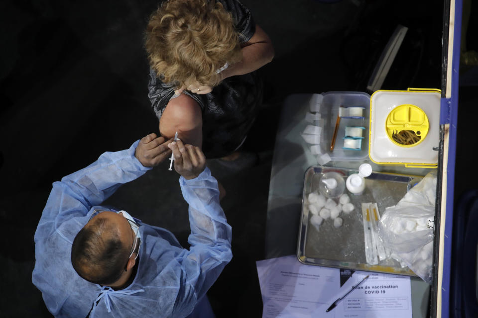 FILE - In this March 29, 2021 file photo, a woman receives Pfizer's COVID-19 vaccine at the National Velodrome in Saint-Quentin-en-Yvelines, west of Paris. Social media influencers in France with hundreds of thousands of followers say a mysterious advertising agency offered to pay them if they agreed to smear Pfizer's COVID-19 vaccine with negative fake stories. The smear effort drew a withering response from French Health Minister Olivier Veran, who called it "pathetic." (AP Photo/Christophe Ena, File)