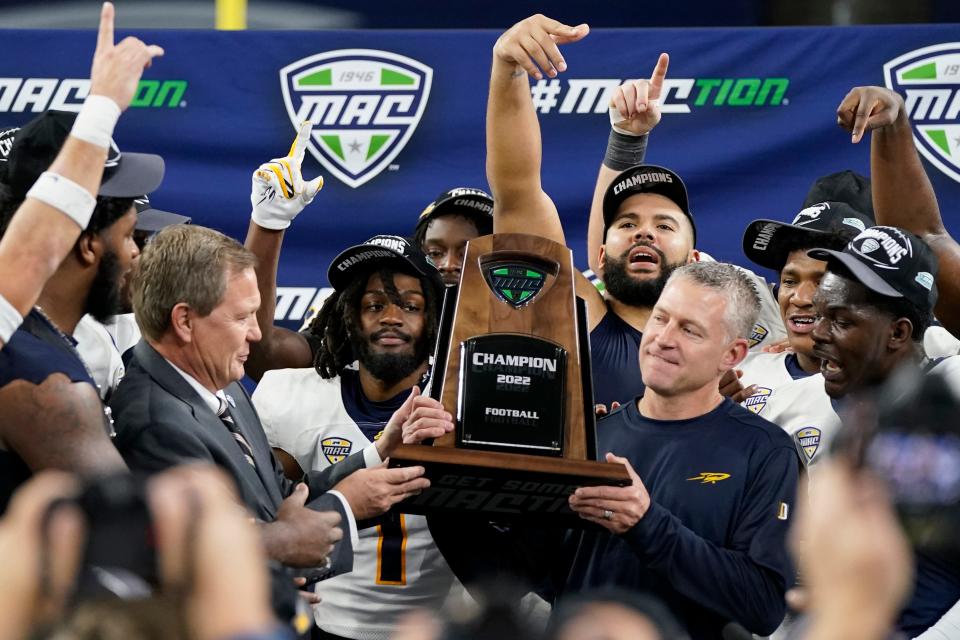 Toledo head coach Jason Candle is presented the championship trophy by commissioner Jon Steinbrecher after the Mid-American Conference championship NCAA college football game against Ohio, Saturday, Dec. 3, 2022, in Detroit. (AP Photo/Carlos Osorio)