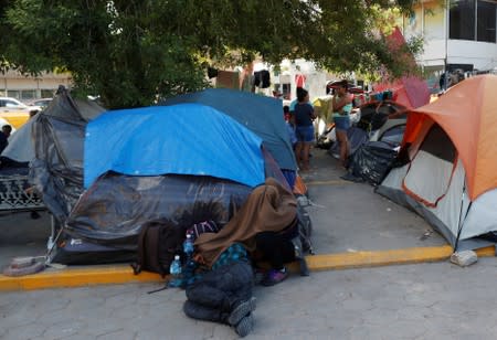 Central American migrants rest outside their tents in an encampment in Matamoros