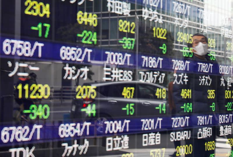 A man is reflected on a stock quotation board in Tokyo