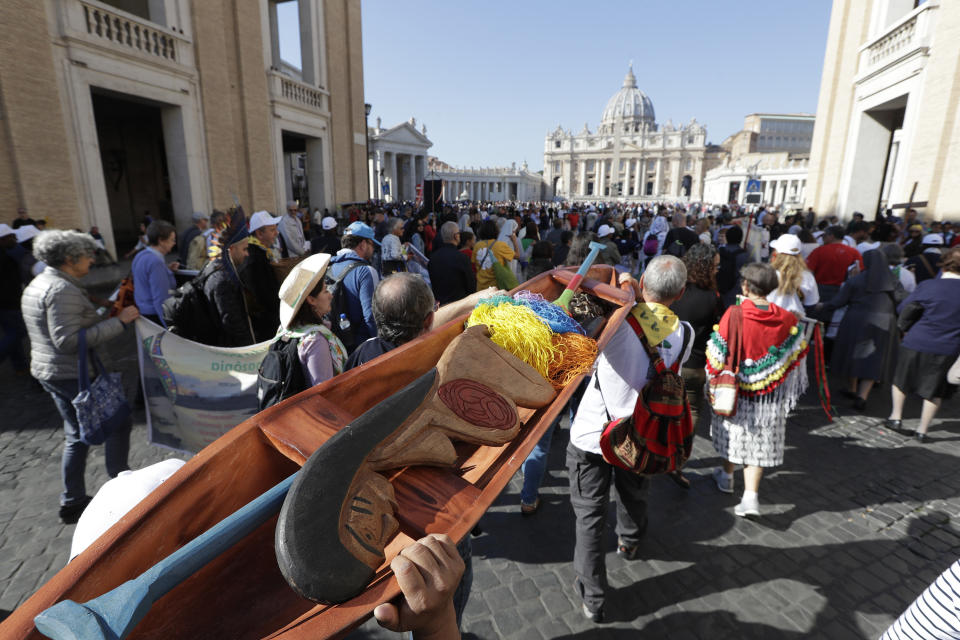 In this photo taken on Saturday, Oct. 19, 2019, members of Amazon indigenous populations walk during a Via Crucis (Way of the Cross) procession from St. Angelo Castle to the Vatican. In foreground is a wooden statue portraying a naked pregnant woman. Pope Francis’ meeting on the Amazon is wrapping up after three weeks of debate over married priests, the environment _ and the destruction of indigenous statues that underscored the willingness of conservatives to violently vent their opposition to the pope. (AP Photo/Andrew Medichini)
