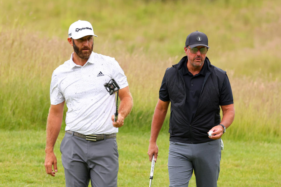 ST ALBANS, ENGLAND - JUNE 09: Dustin Johnson of 4 Aces GC greets Phil Mickelson of Hy Flyers GC look on on the 4th green during day one of the LIV Golf Invitational - London at The Centurion Club on June 09, 2022 in St Albans, England. (Photo by Chris Trotman/LIV Golf/Getty Images)