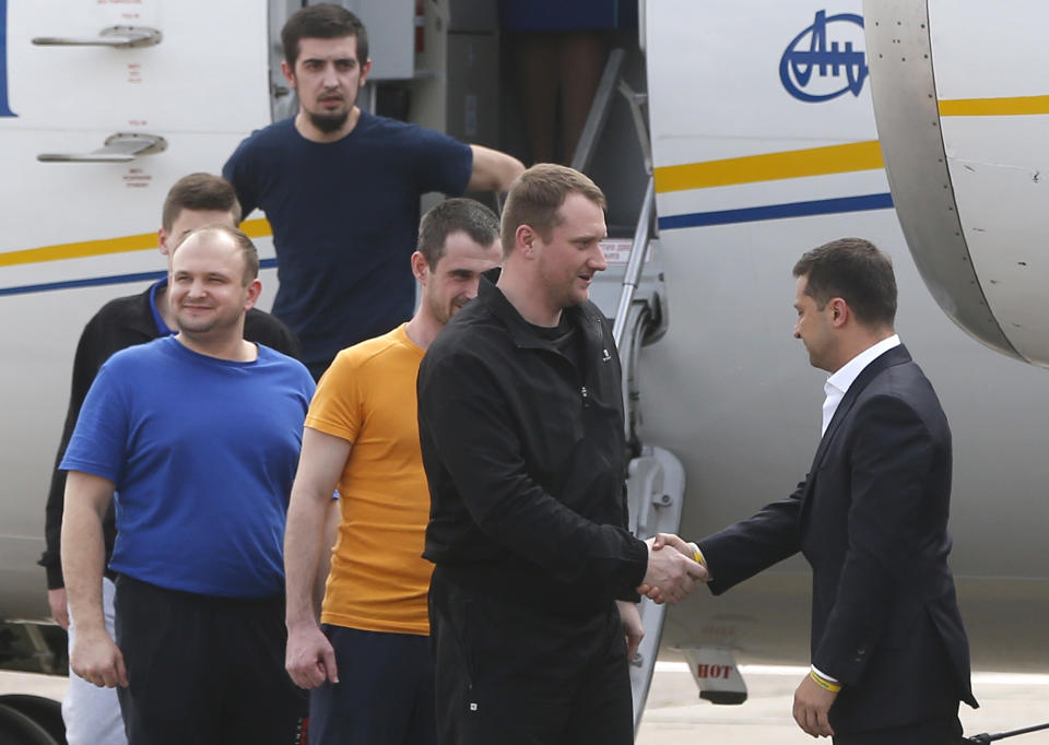 Ukraine's President Volodymyr Zelenskiy, right, greets Ukrainian prisoners upon their arrival at Boryspil airport, outside Kyiv, Ukraine, Saturday, Sept. 7, 2019. Planes carrying prisoners freed by Russia and Ukraine have landed in the countries' capitals, in an exchange that could be a significant step toward improving relations between Moscow and Kyiv. The planes, each reportedly carrying 35 prisoners, landed almost simultaneously at Vnukovo airport in Moscow and at Kyiv's Boryspil airport. (AP Photo/Efrem Lukatsky)