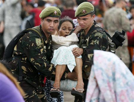 Soldiers carry an injured woman on to a U.S. Marines C-130 aircraft bound for Manila on the runway of the Tacloban airport November 14, 2013, in the aftermath of super typhoon Haiyan. REUTERS/Wolfgang Rattay