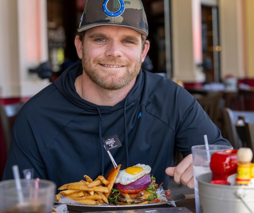 IndyCar Series driver Conor Daly, with the Model “A” burger at Ford’s Garage in Noblesville, Monday, Oct 23, 2023. The sandwich, which includes bacon, salsa, and a sunny side up egg, is locally named for Daly.